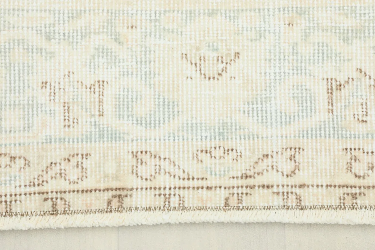 Close-up detail of the rug's border showing light blue and beige patterns