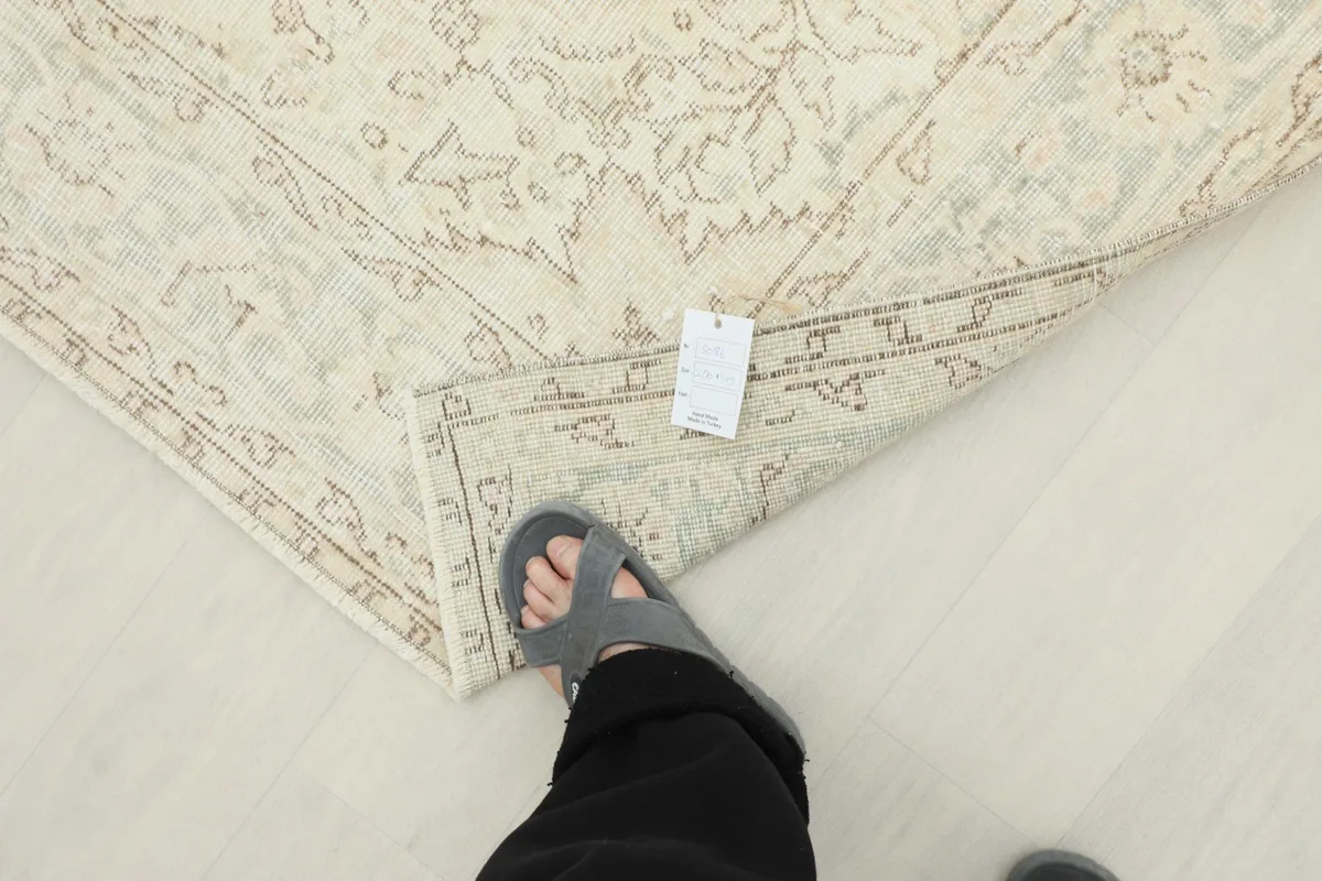 View of the rug's back and foundation, with a foot for scale