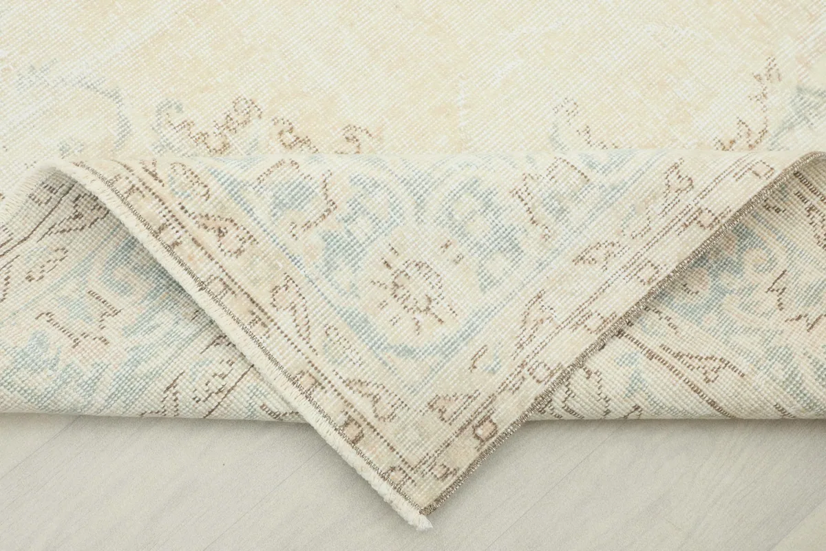 Corner of the rug folded back to show the cotton foundation and reverse side