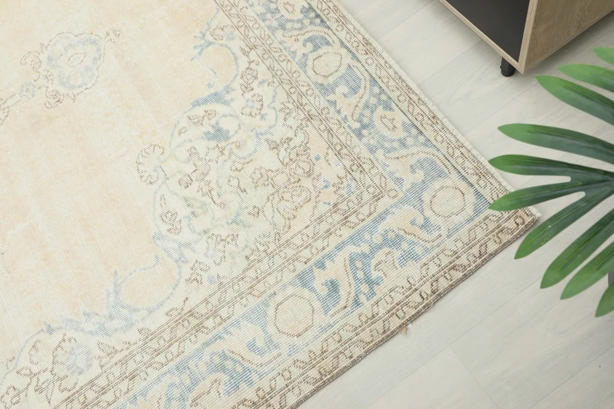 Detailed view of the blue border pattern and cream field of the rug