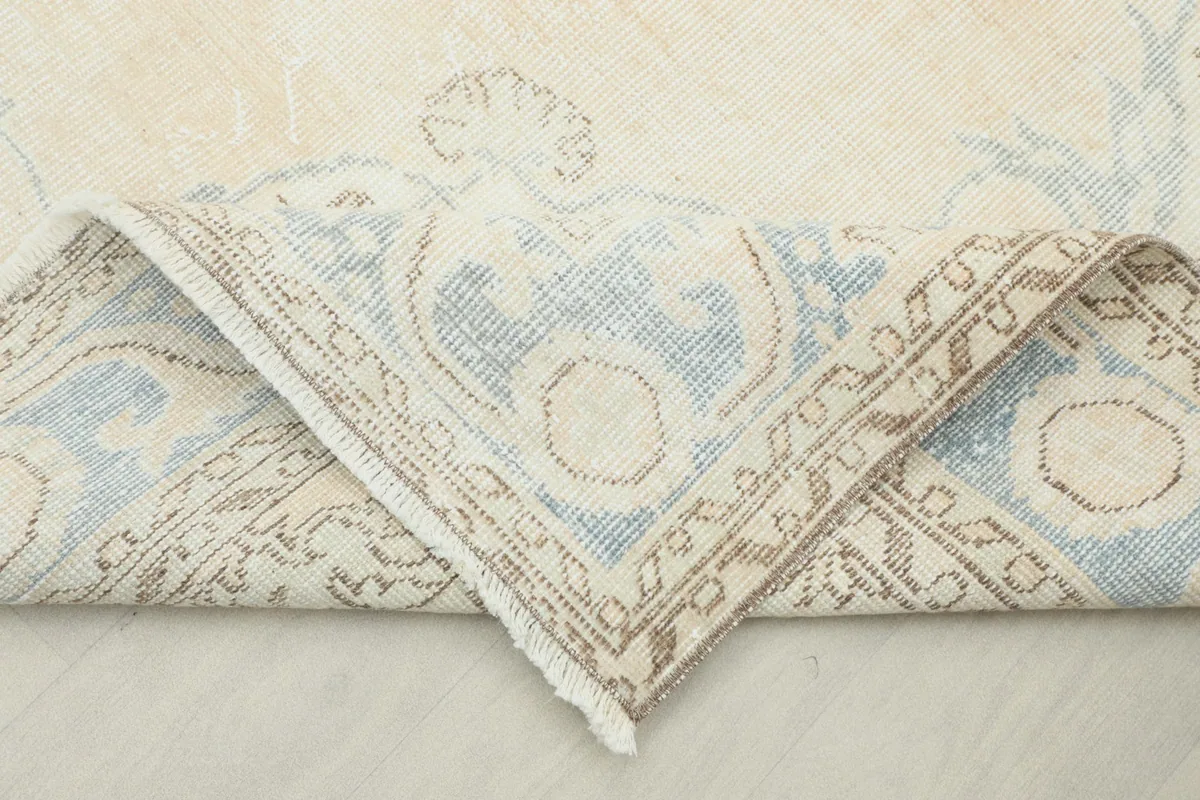 Corner of the rug folded to show the hand-knotted construction and texture