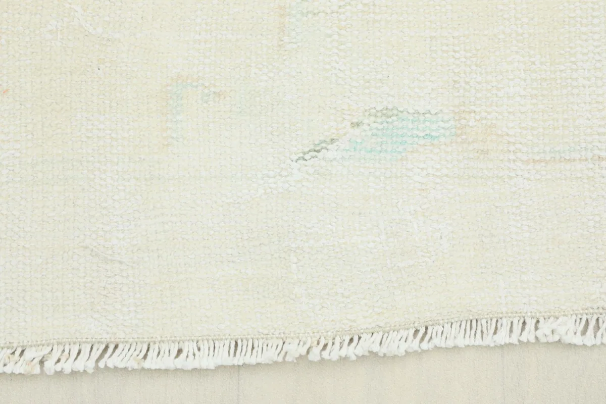 Close-up view of the natural ivory fringe and edge of the hand-knotted wool rug
