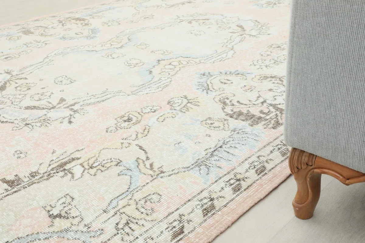Angled view of the rug's surface, showing its soft colors and pattern next to a sofa