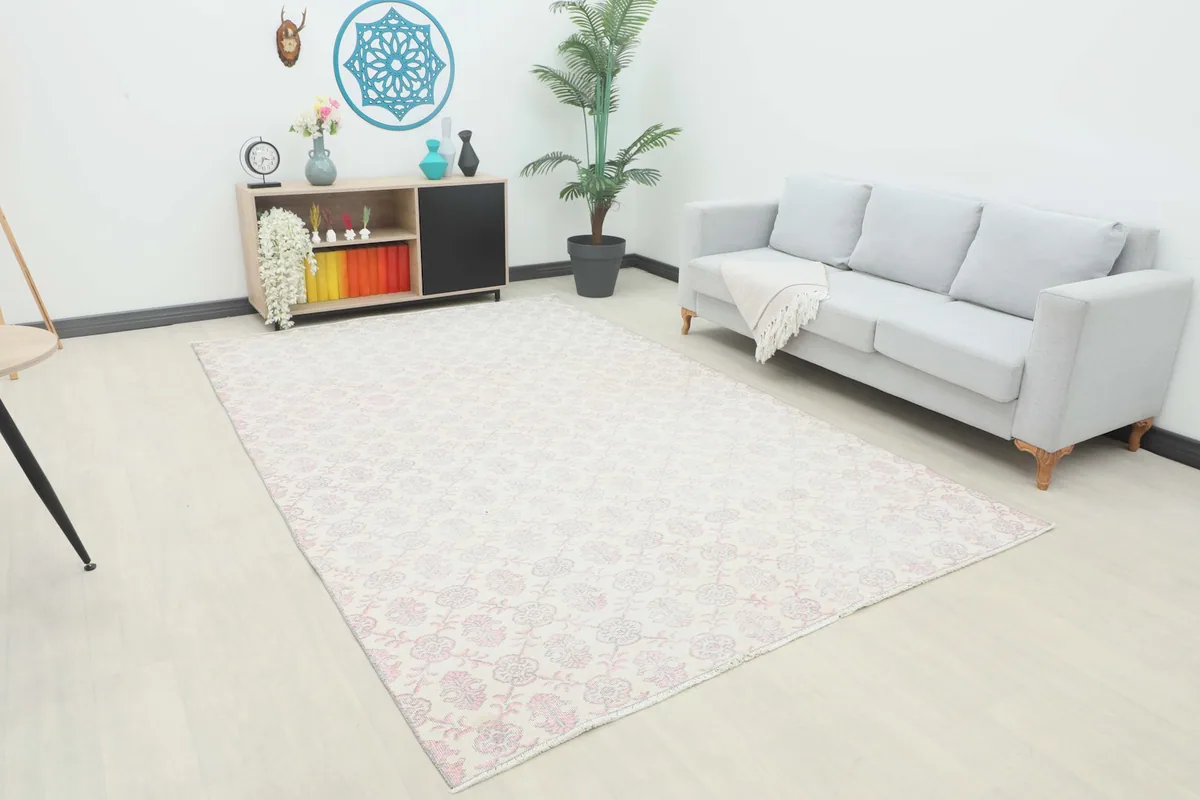 The large ivory and rose rug displayed in a modern living room setting with a light gray sofa.
