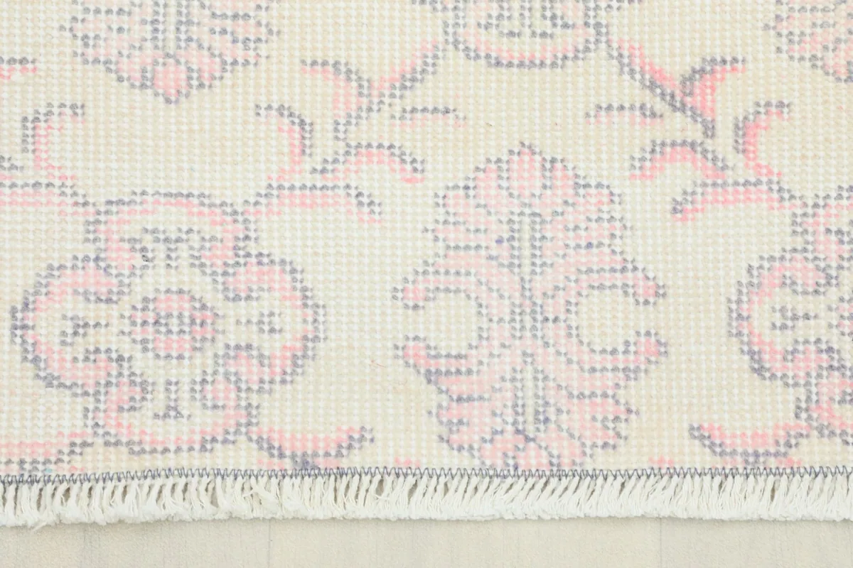 Close-up detail of the rug's rose and gray floral pattern and fringe.