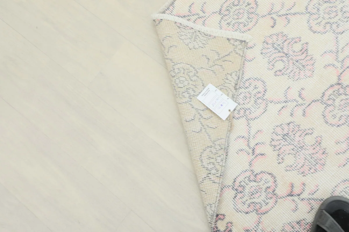 Underside of the rug partially shown with a label, indicating its hand-knotted construction.