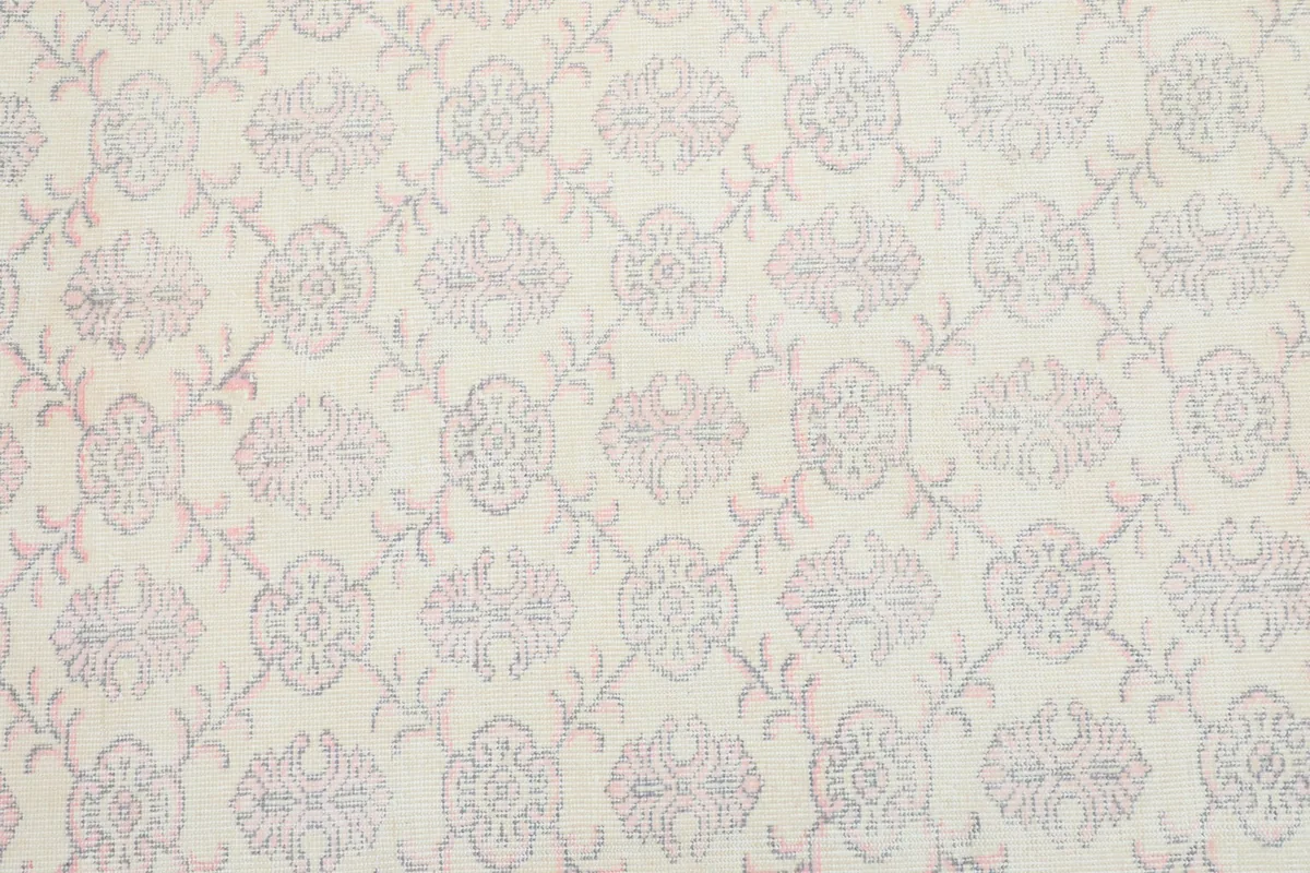 Overhead view showing the subtle floral and geometric pattern across the rug's ivory field.