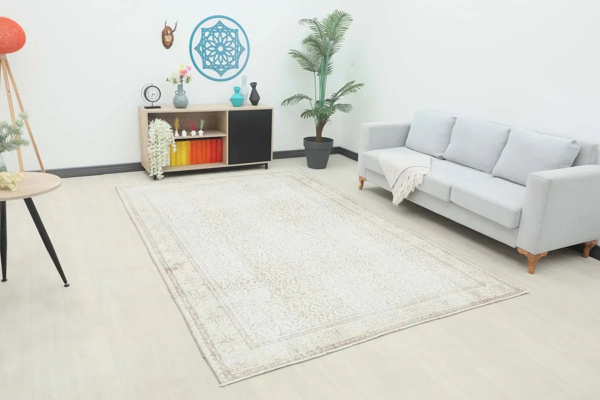 Vintage cream and tan rug displayed in a living room setting with a light gray sofa