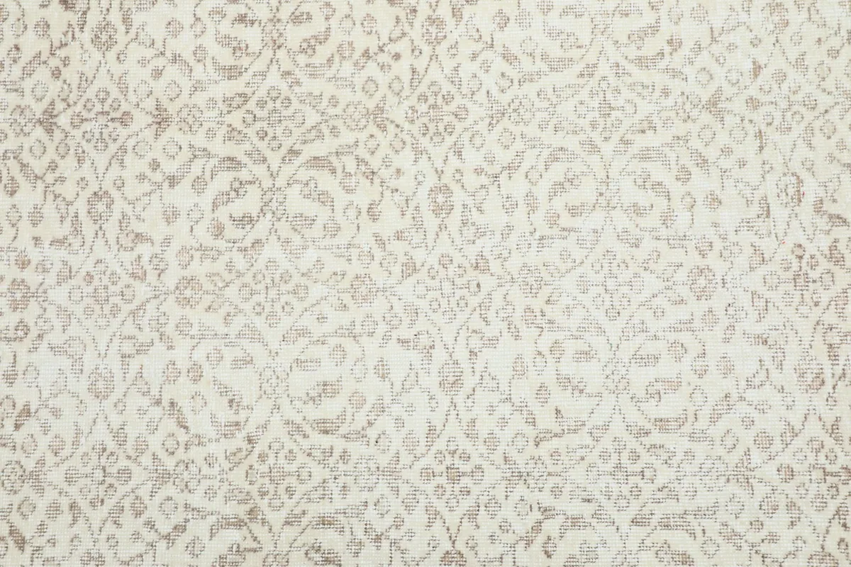 Detailed view of the repeating cream and tan floral patterns in the rug's field