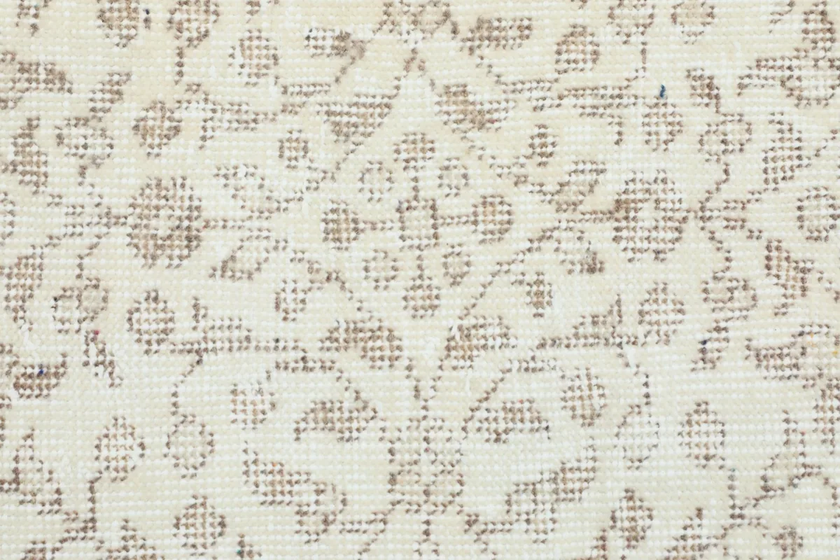 Close-up of the subtle tan geometric and floral motifs on the cream field, showing low pile