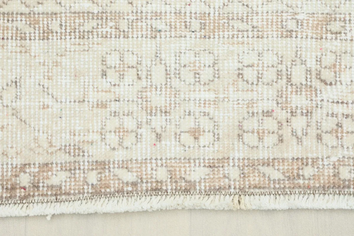 Close-up view of the rug's border showing tan floral and geometric motifs on a cream background