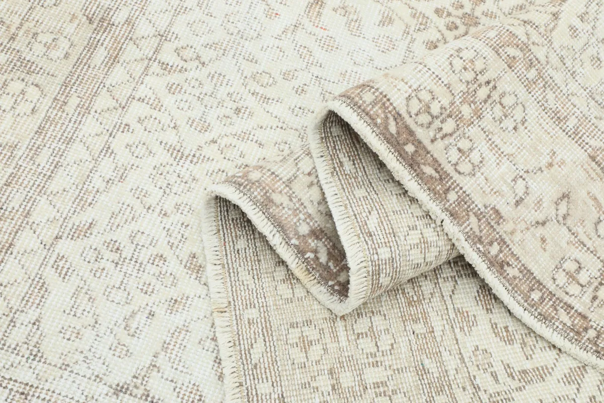 Folded section of the rug, revealing the intricate tan patterns and cream base