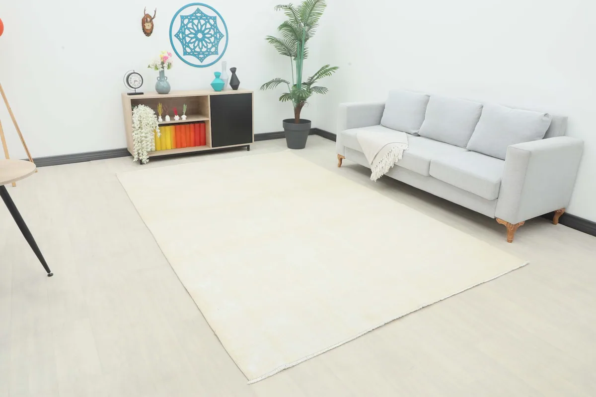 Cream vintage wool rug in a living room setting with a light gray sofa and wooden console