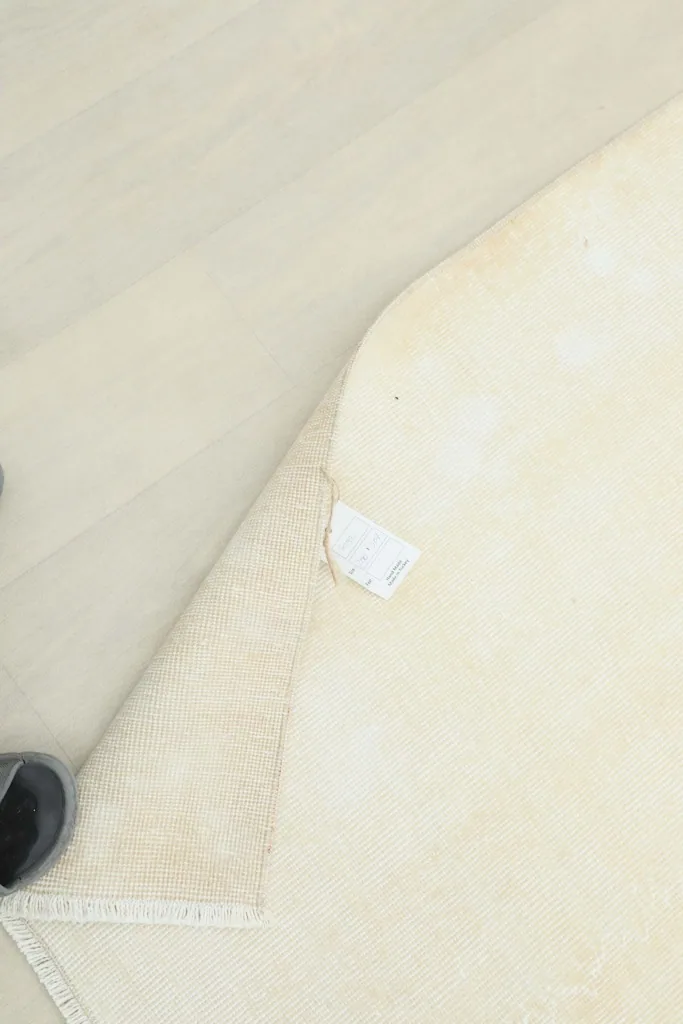 Person lifting a corner of the rug to show the label and the rug's flexibility