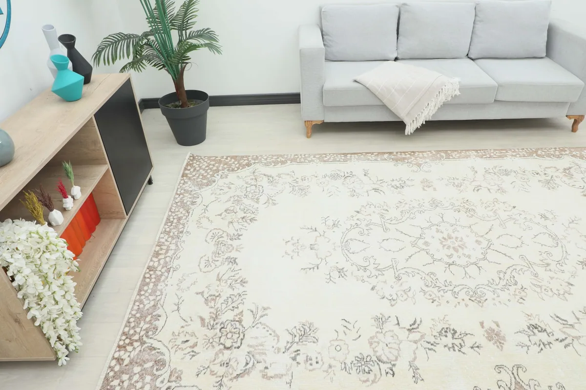 Overhead view of the Cream Tan Botanical Medallion Rug in a room with a sofa and cabinet