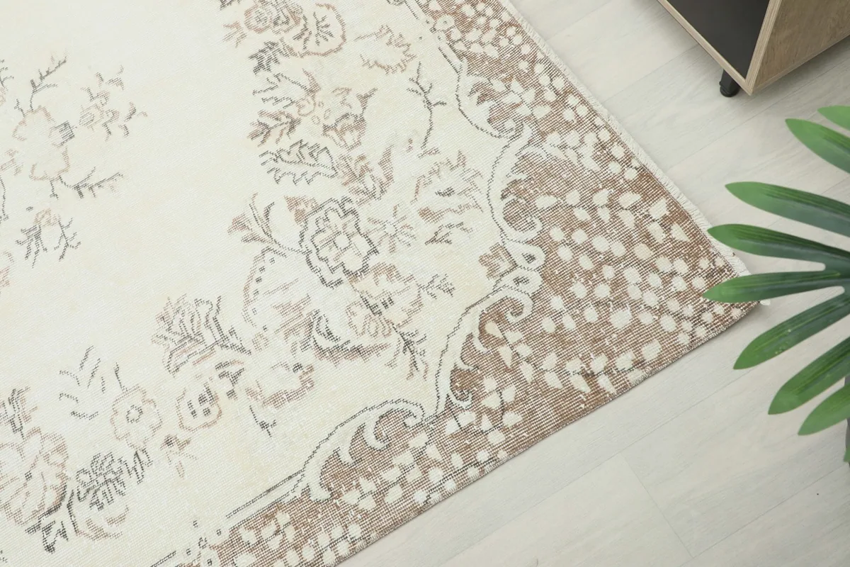 Detail of the rug's tan border with a distressed, mottled texture and botanical elements
