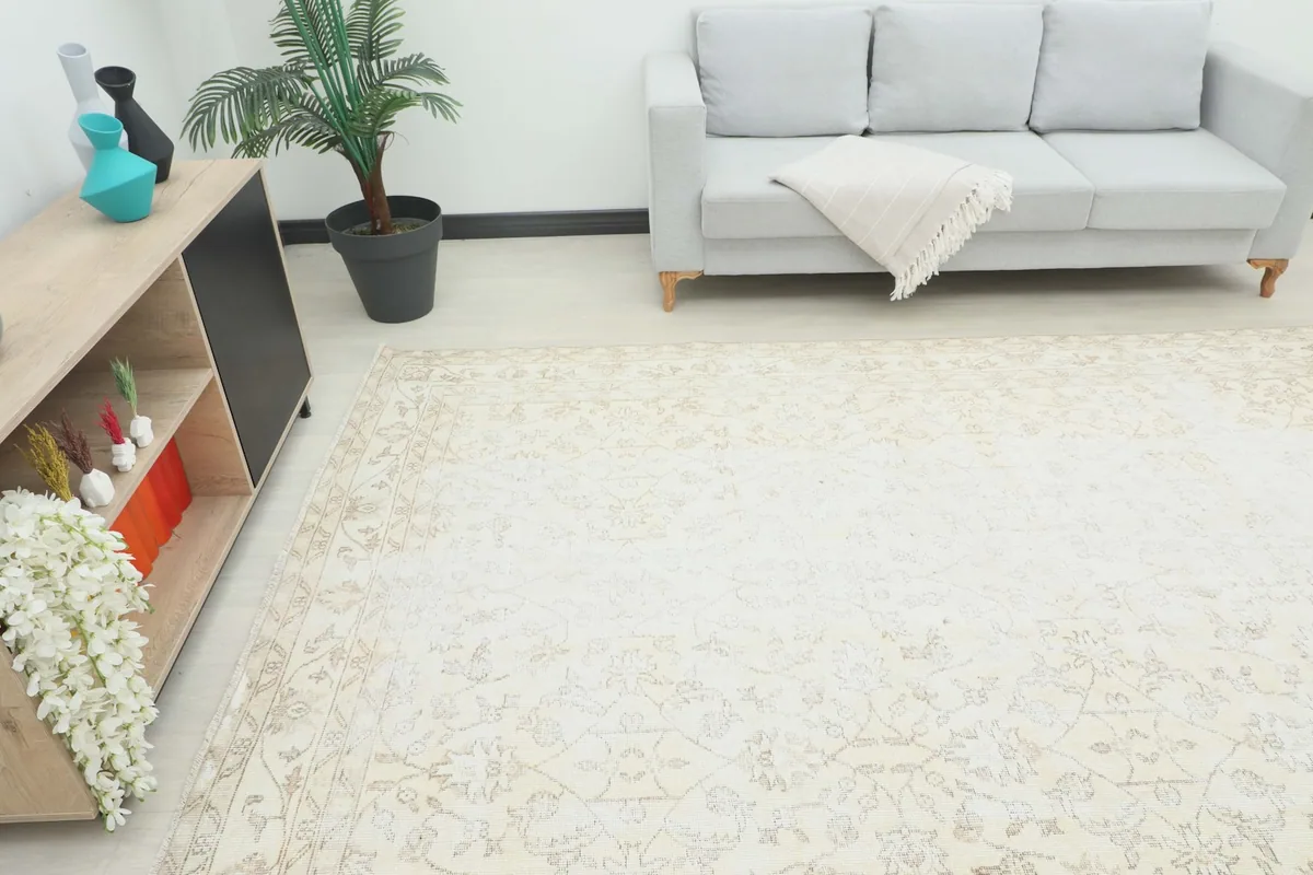 Angled view of the large beige rug in a room, highlighting its placement relative to furniture