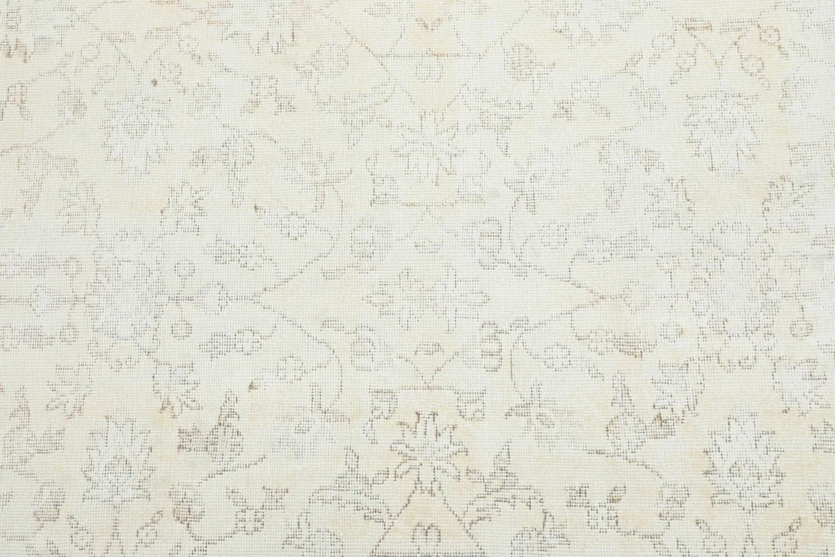 Detailed view of the subtle ivory floral and geometric patterns on the beige rug field