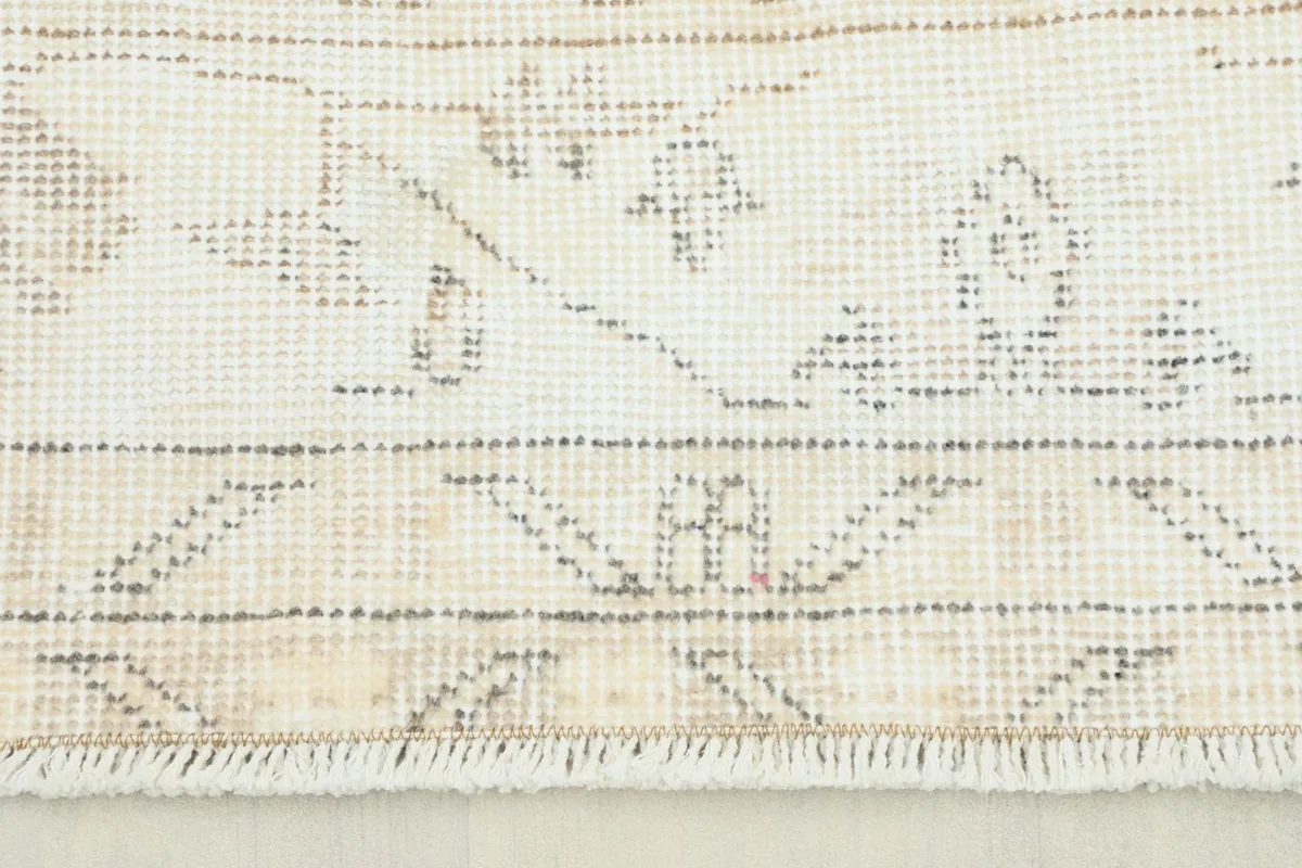Close-up view of the rug's reverse side, showing the hand-knotted cotton foundation and fringe