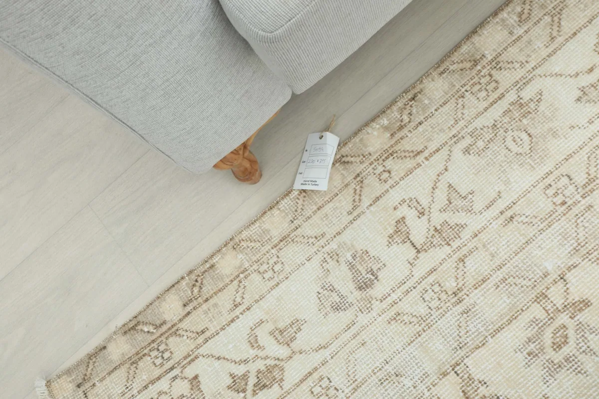 Overhead view of the rug next to a sofa with a tag visible, showing its full width