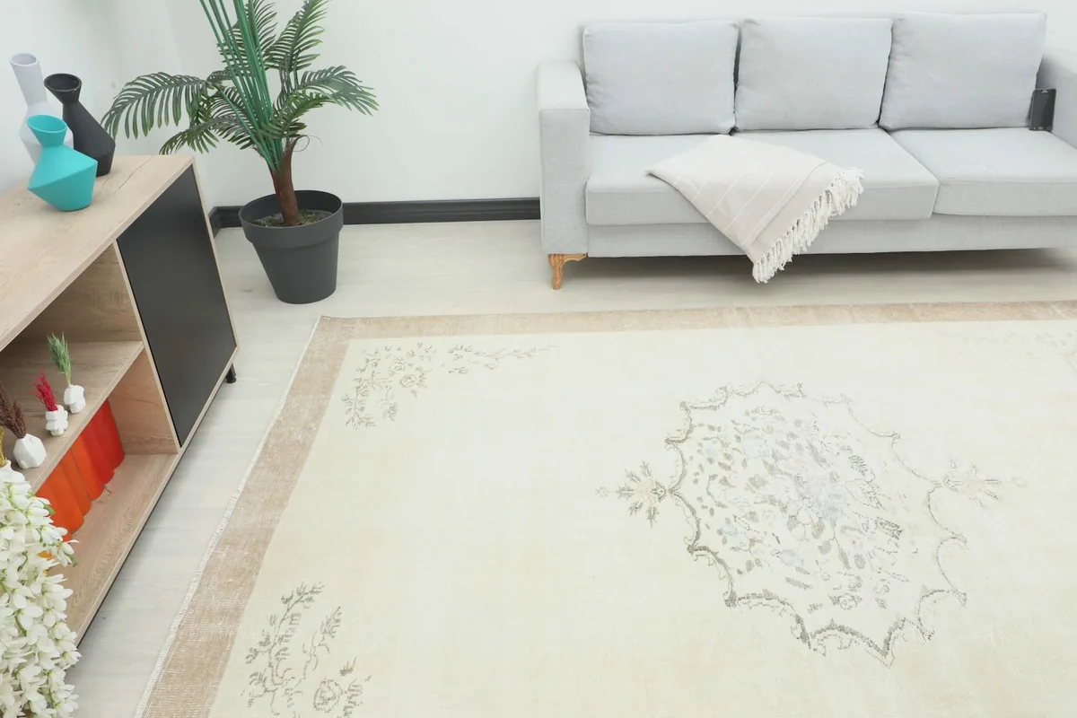 Angle view of the cream vintage rug in a living room, showing its scale next to furniture.