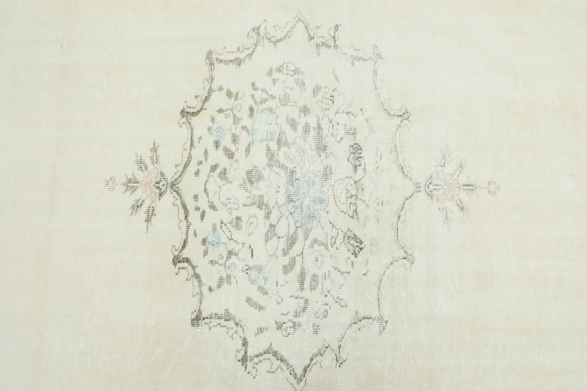 Detailed view of the central floral medallion pattern on the cream field of the rug.