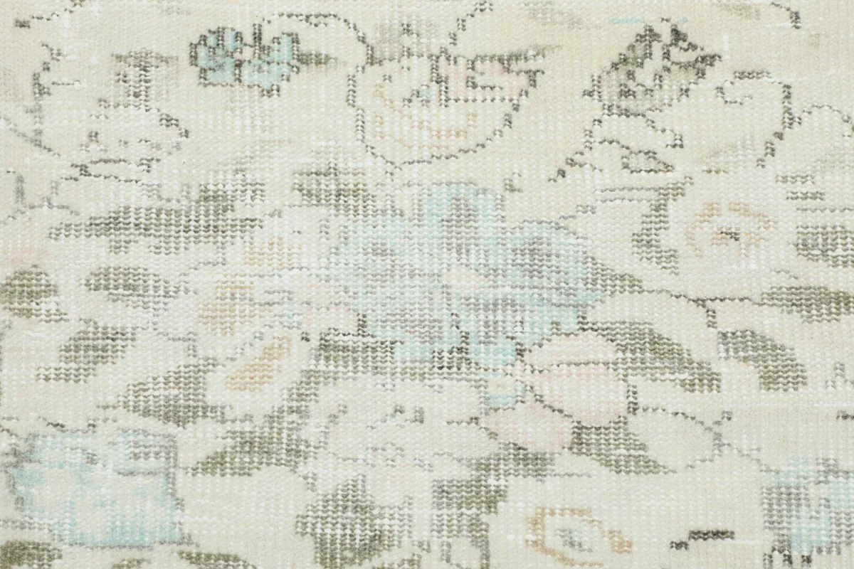 Close-up of the subtle floral patterns and texture on the vintage wool pile rug.