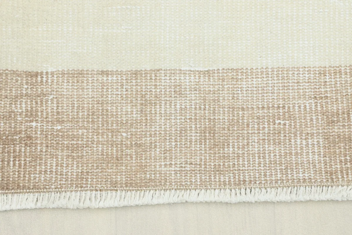 Close-up view of the beige border and cream field of the hand-knotted vintage rug.