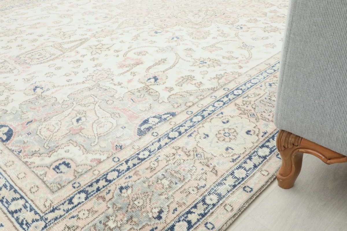 Rug detail next to a sofa leg, showing the border design and overall color palette
