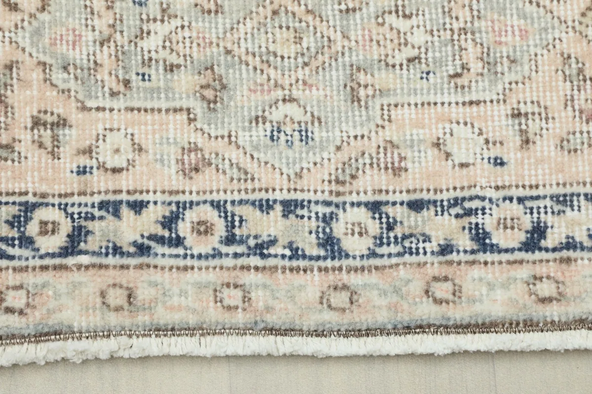 Close-up view of the rug's border showing navy and beige patterns and fringe