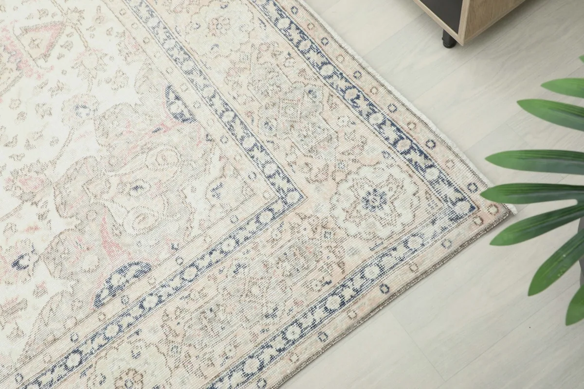 Corner view of the rug's border, highlighting navy and beige patterns against the ivory field