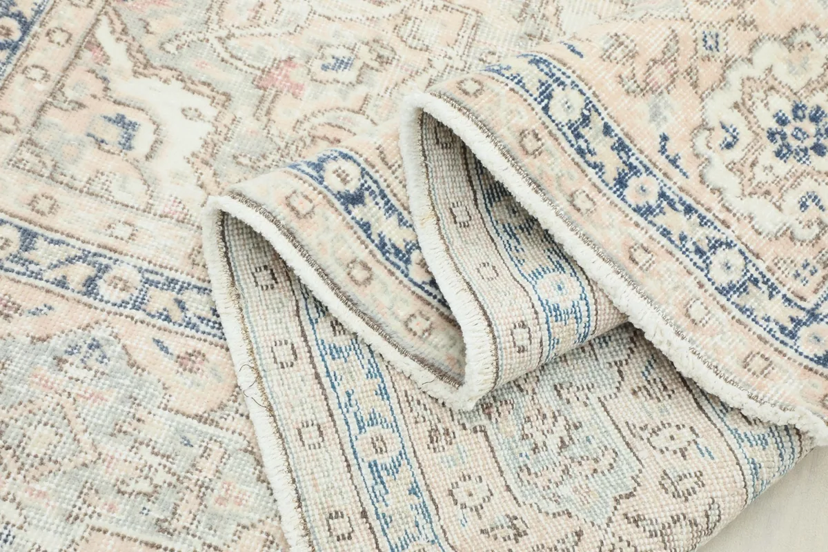Close-up of the low wool pile and intricate patterns, with a rolled section of the rug