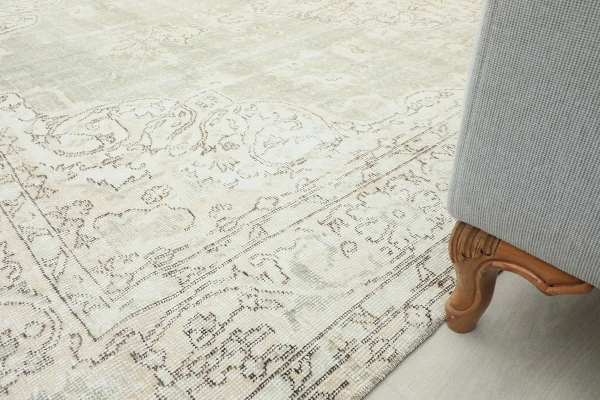 Close-up of the rug's edge next to a sofa leg, illustrating the low pile and vintage patina.