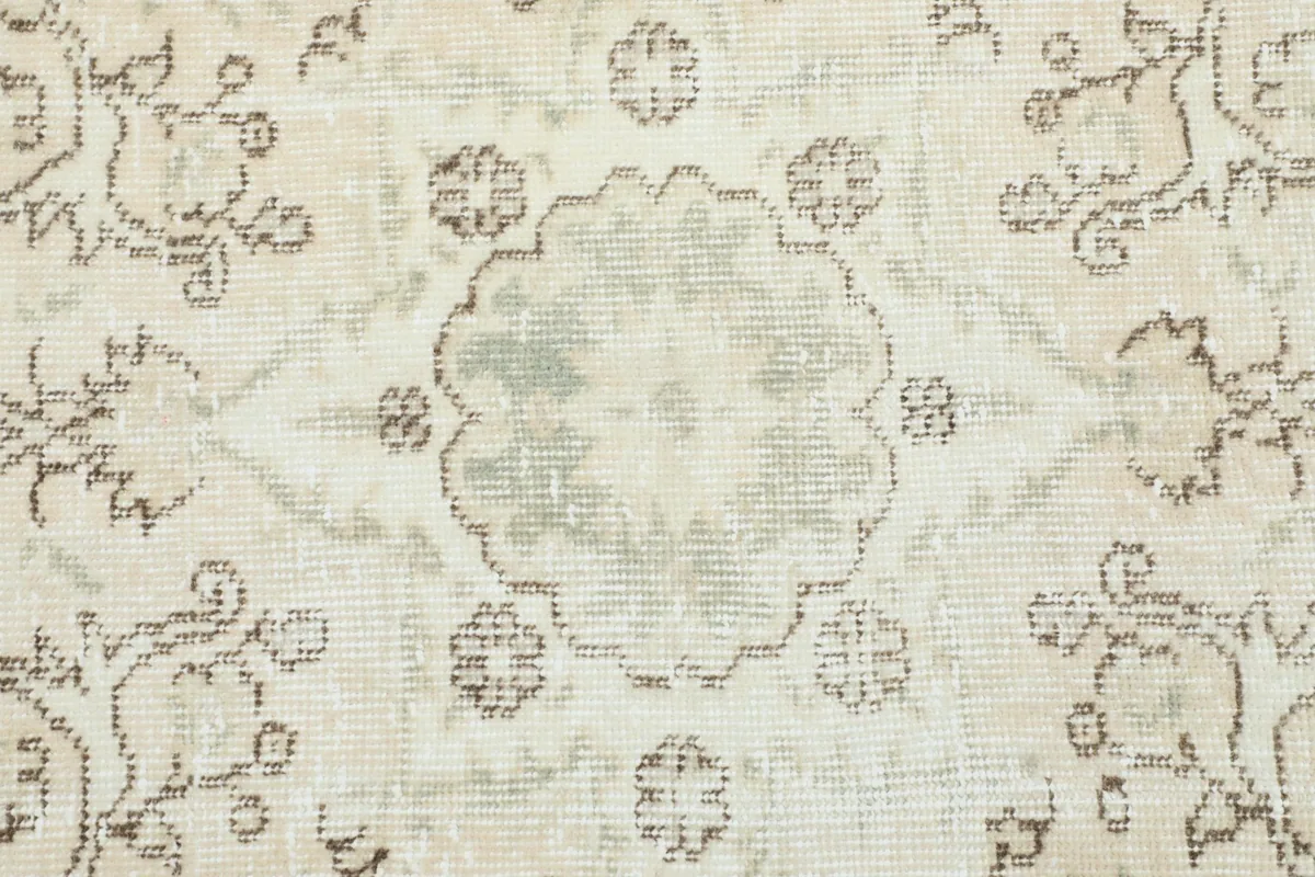 Close-up of the floral and geometric motifs on the rug, highlighting the aged texture and colors.