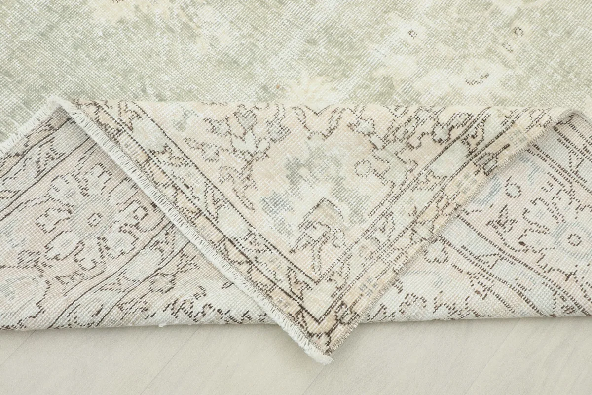 Corner of the rug folded to show the hand-knotted construction and back of the wool pile.