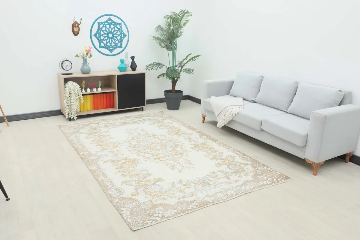 Ivory gold floral vintage rug displayed in a living room setting with a light gray sofa and plant.