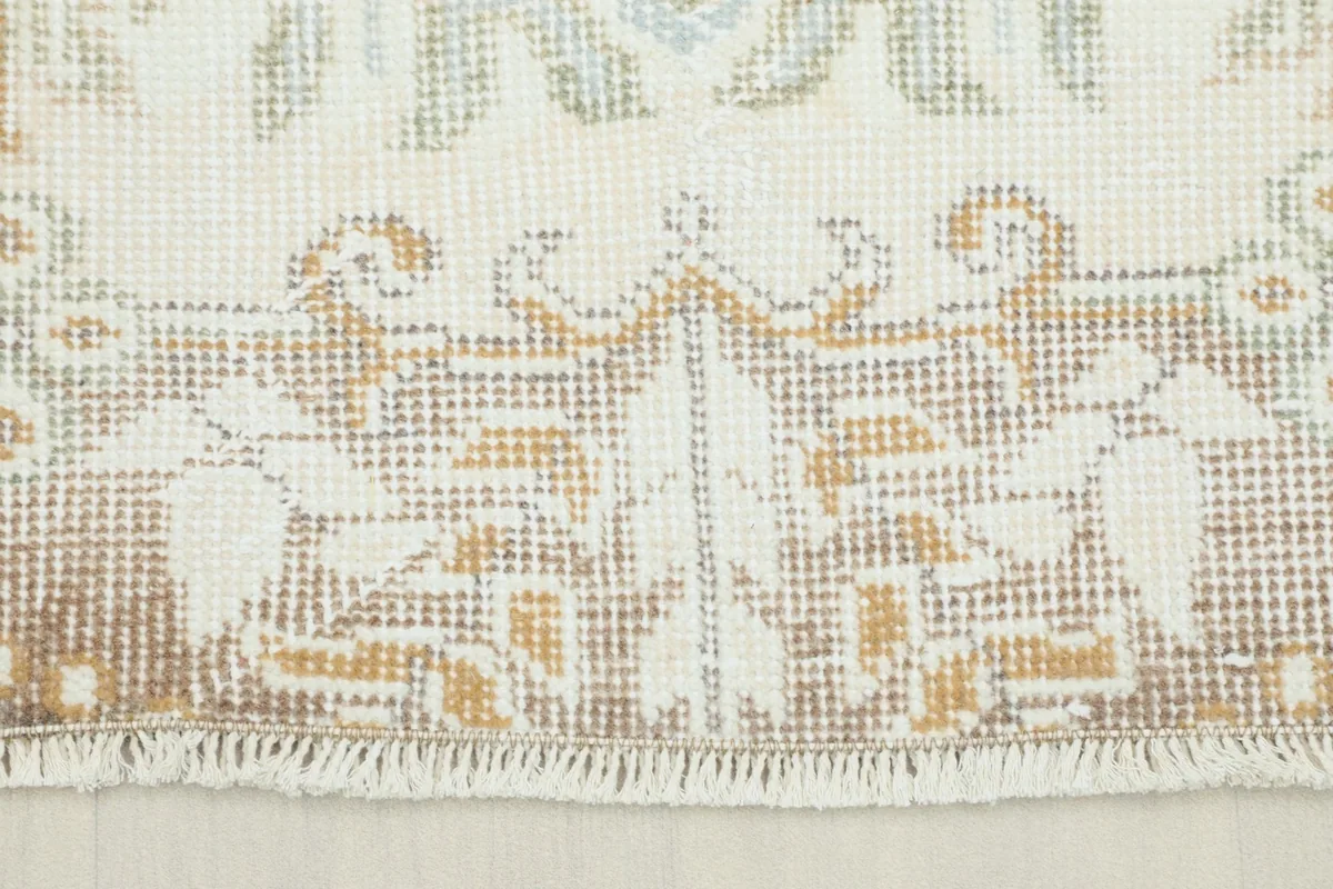 Close-up view of the rug's short fringe and the detailed tan and brown border pattern.