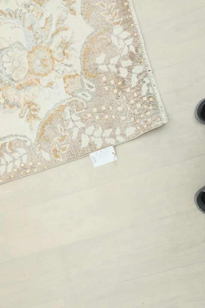 Close-up of the rug's edge, showing a small white tag and the detail of the tan and brown border.
