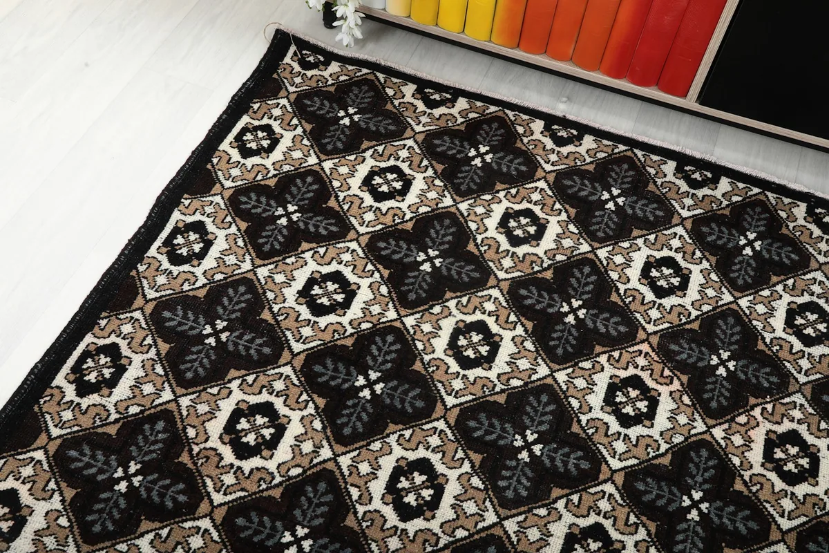 Corner view of the vintage rug highlighting its black border and patterned field