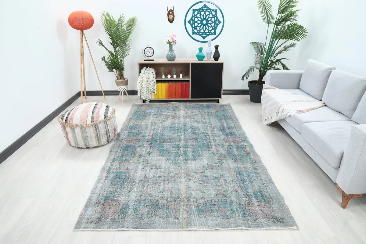 Vintage rug displayed in a living room setting, showing its scale next to a sofa and furniture.