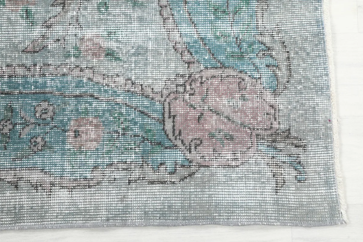 Close-up of the rug's border and corner, revealing the rose and blue floral patterns.