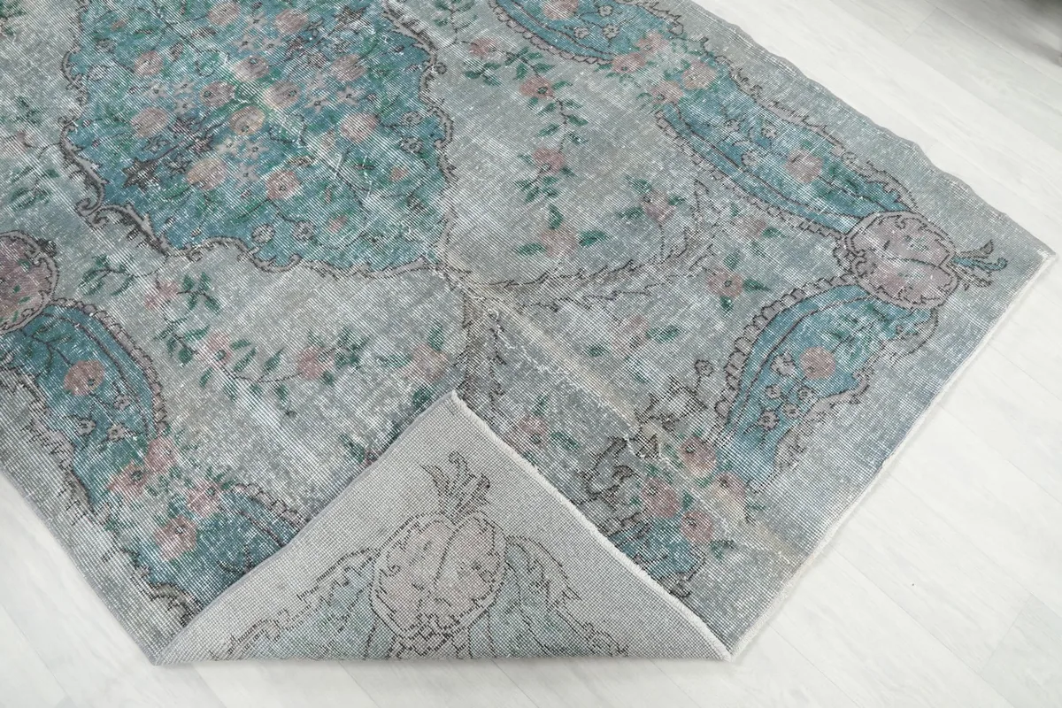 Corner of the rug folded back, showing the back of the hand-knotted cotton foundation.
