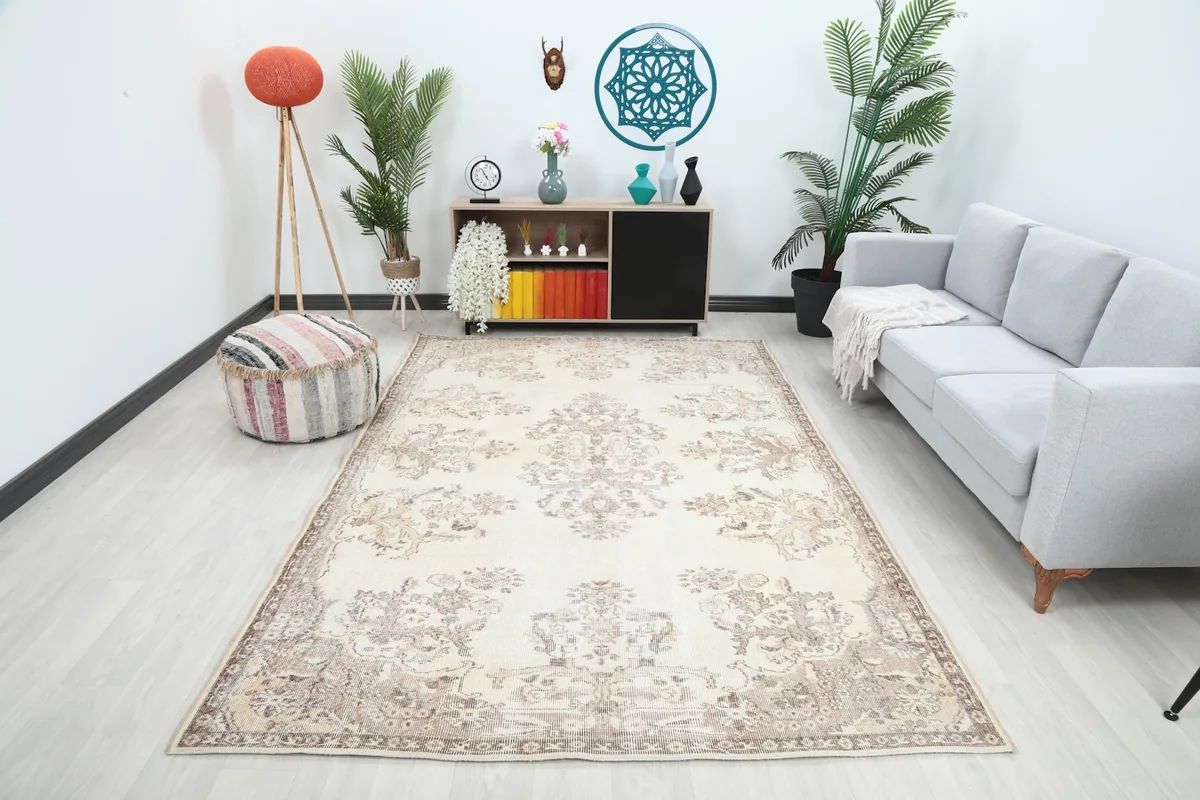 Vintage ivory and tan rug in a living room setting with a gray sofa
