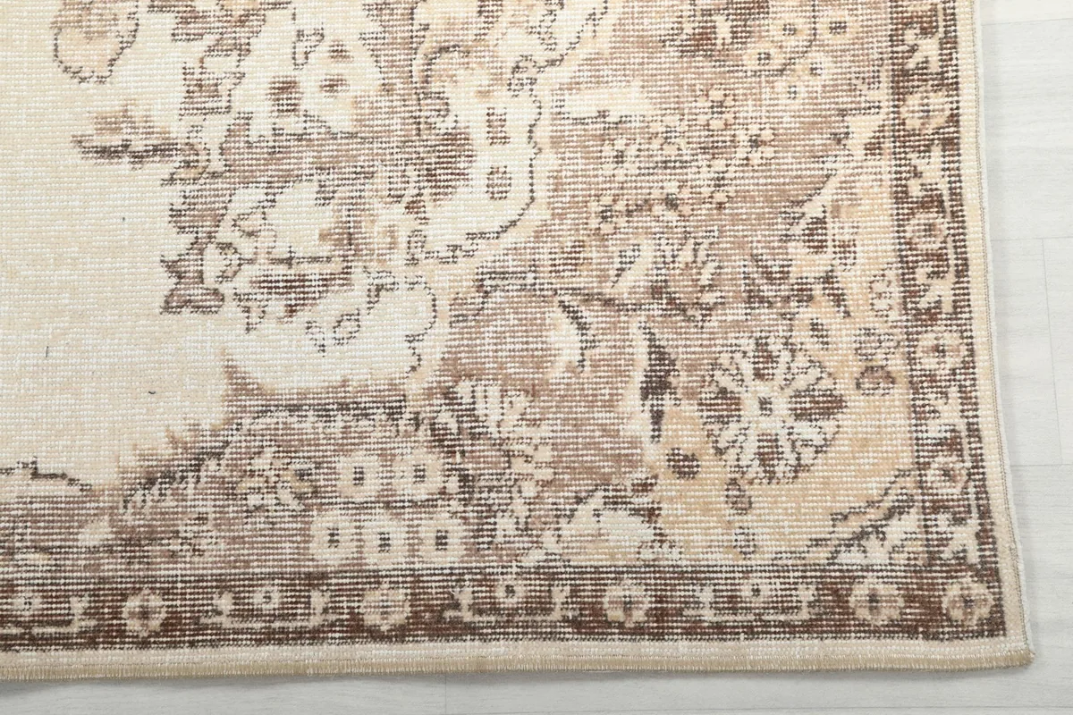 Detail view of the distressed tan and brown floral patterns on the rug's border