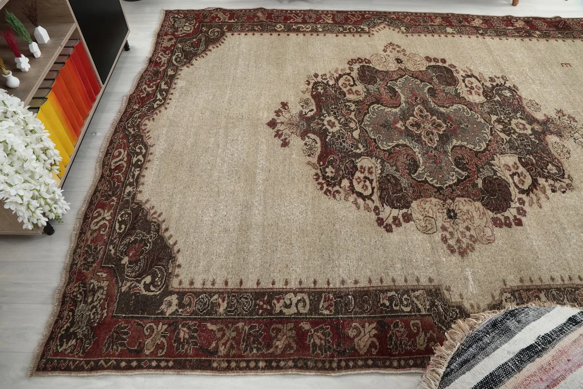 Wide angle view capturing the texture and colors of the ivory and red vintage rug on the floor