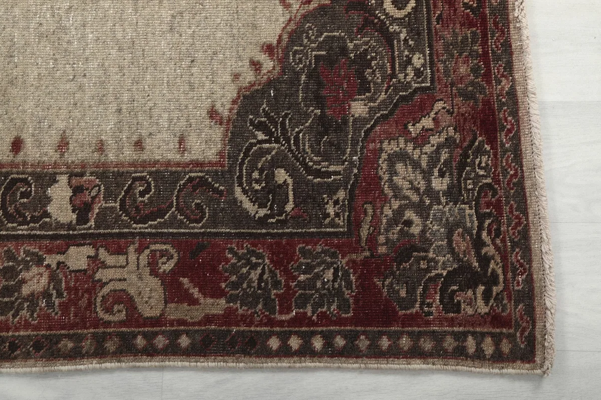 Detail of the red and brown border pattern with geometric and floral motifs on the vintage rug