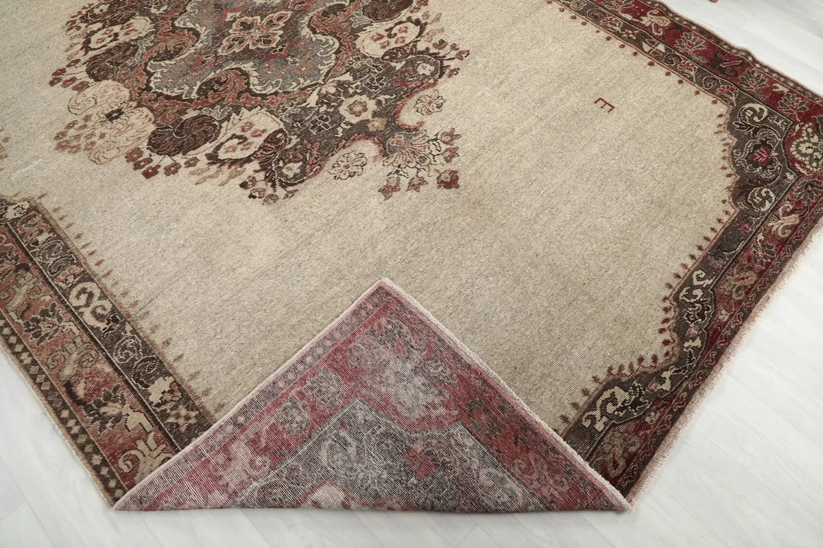 Corner of the vintage rug folded to reveal the hand-knotted wool pile and cotton foundation