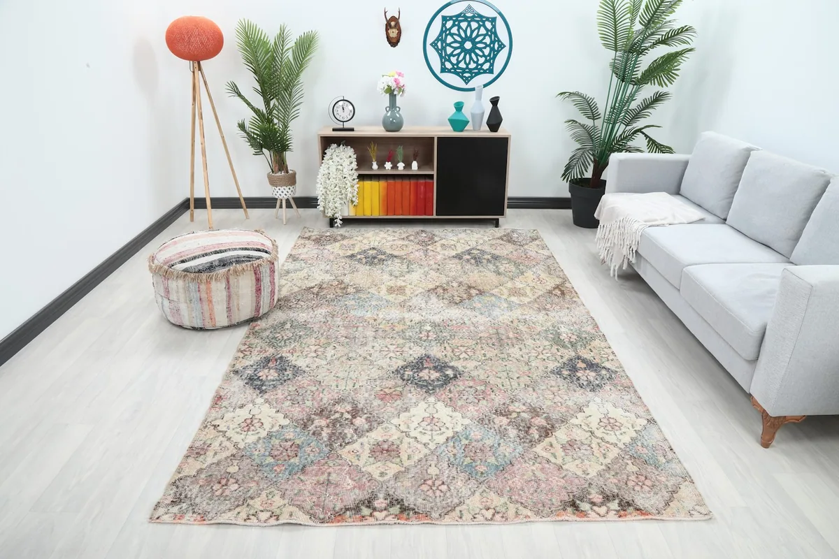 Multicolor vintage area rug displayed in a bright living room setup with a sofa and pouf