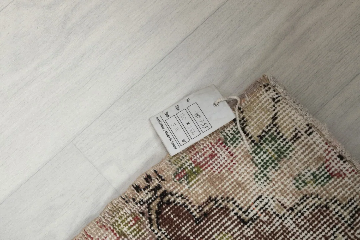 Rug corner with product tag displaying size and material details on a light floor