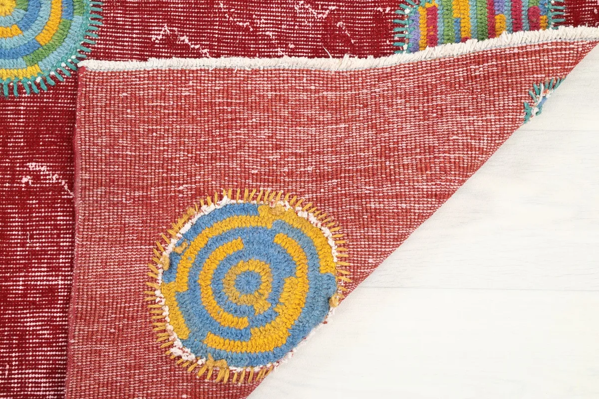 Detailed view of the rug's back, showing craftsmanship and a geometric patch from the reverse side
